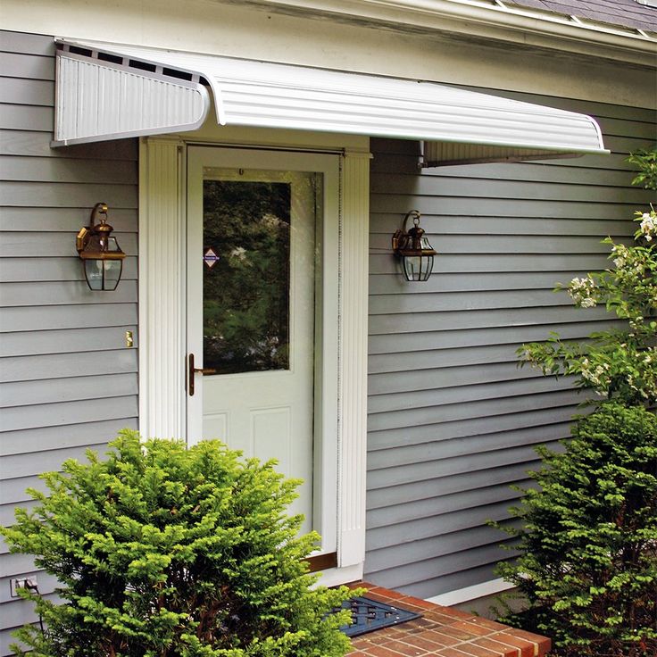 the front door of a gray house with white trim and an awning over it