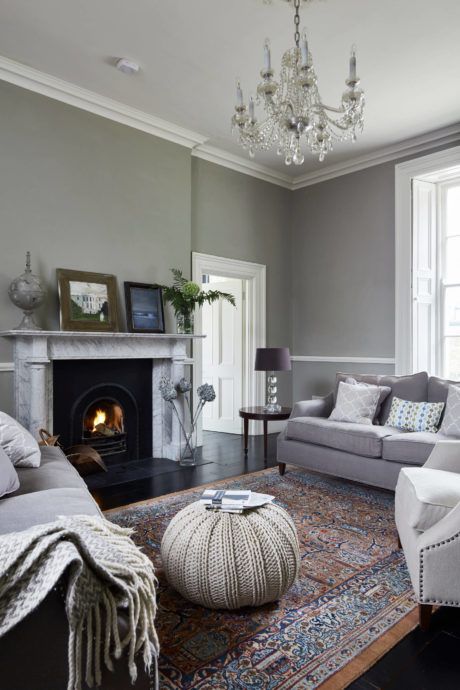 a living room filled with furniture and a fire place under a chandelier in front of a window