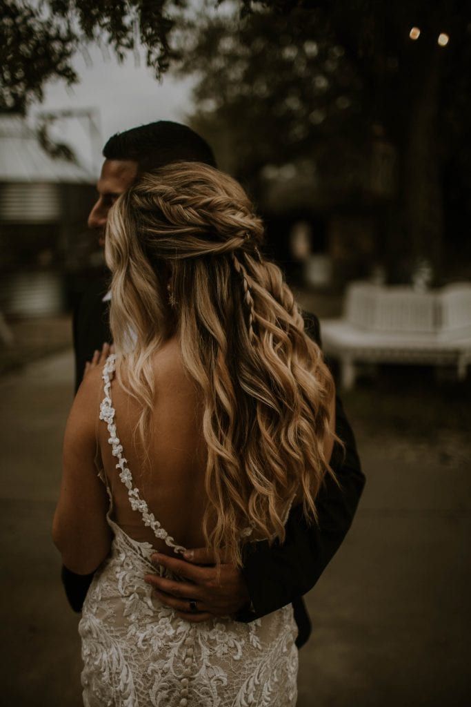 the back of a bride's dress as she hugs her groom on their wedding day