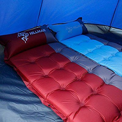 an inflatable bed is set up inside a tent with blue walls and red pillows