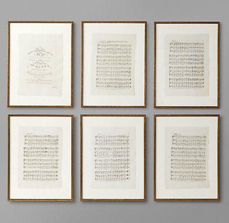 six framed music manuscripts in gold frames against a gray wall with white writing on them