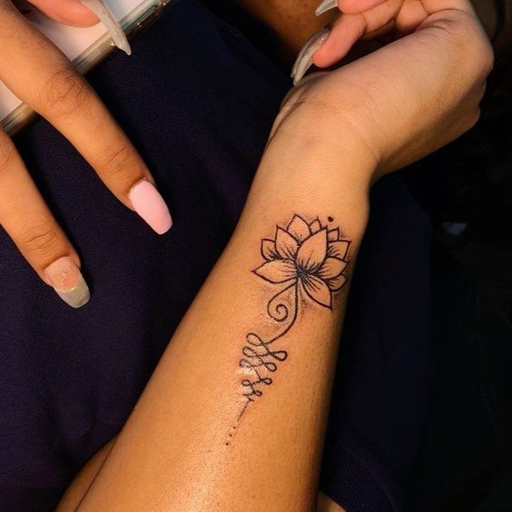 a woman's arm with a flower tattoo on the left side of her wrist