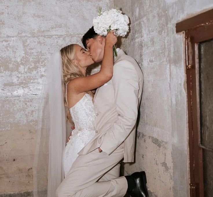 a bride and groom kissing in front of a wall with the words i wish i were with kylie all the time