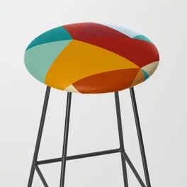 a multicolored stool sitting on top of a white floor next to a wall