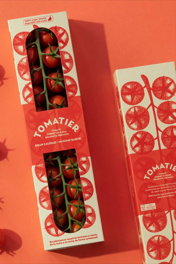 two boxes of tomatoes sitting next to each other on a pink surface, with one box open