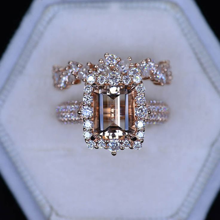 a fancy ring with an emerald center surrounded by white and brown diamonds in a hexagonal box