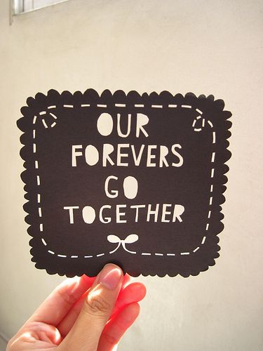 a hand holding up a sign that says our forevers go together on the front