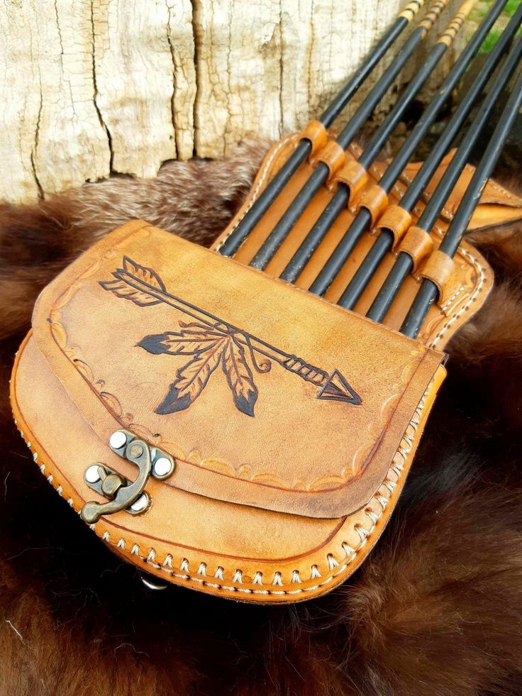 a leather case with arrows on it sitting on a fur covered surface next to a wooden wall