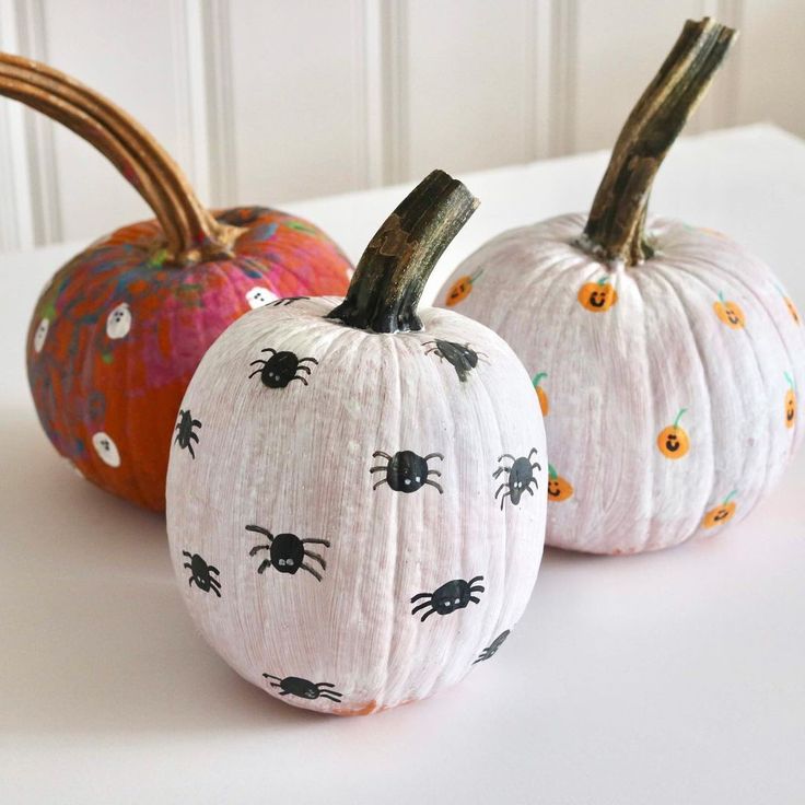 two white pumpkins decorated with black spider faces