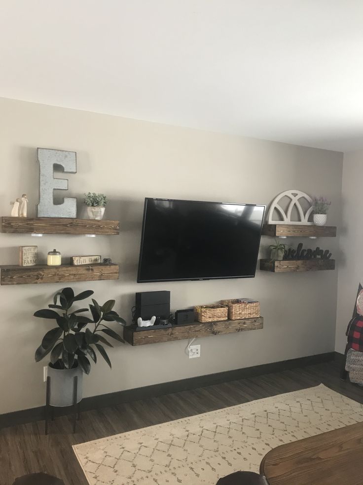 a flat screen tv mounted to the wall in a living room next to a potted plant