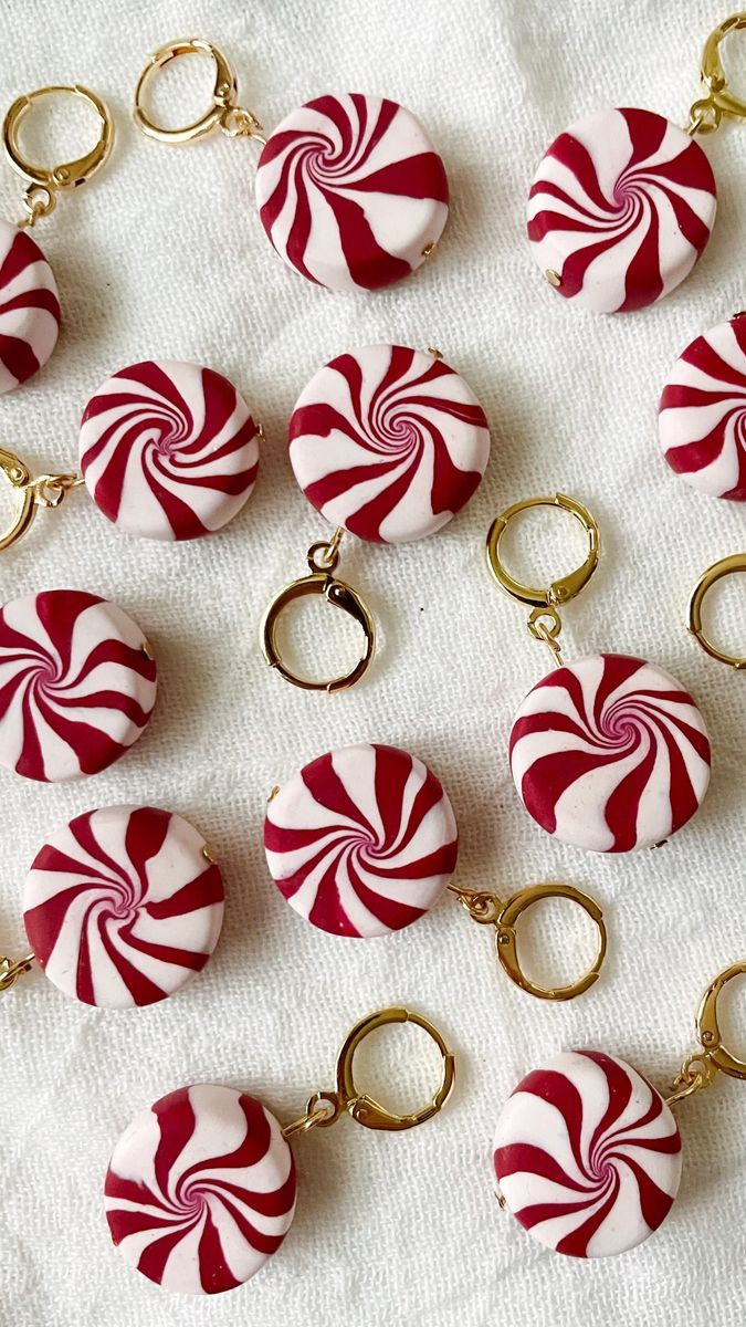 red and white candy cane keychains with gold rings on a white cloth background