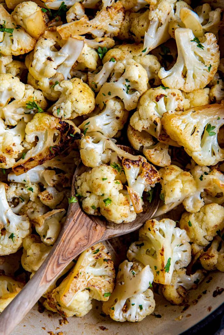 roasted cauliflower in a pan with a wooden spoon