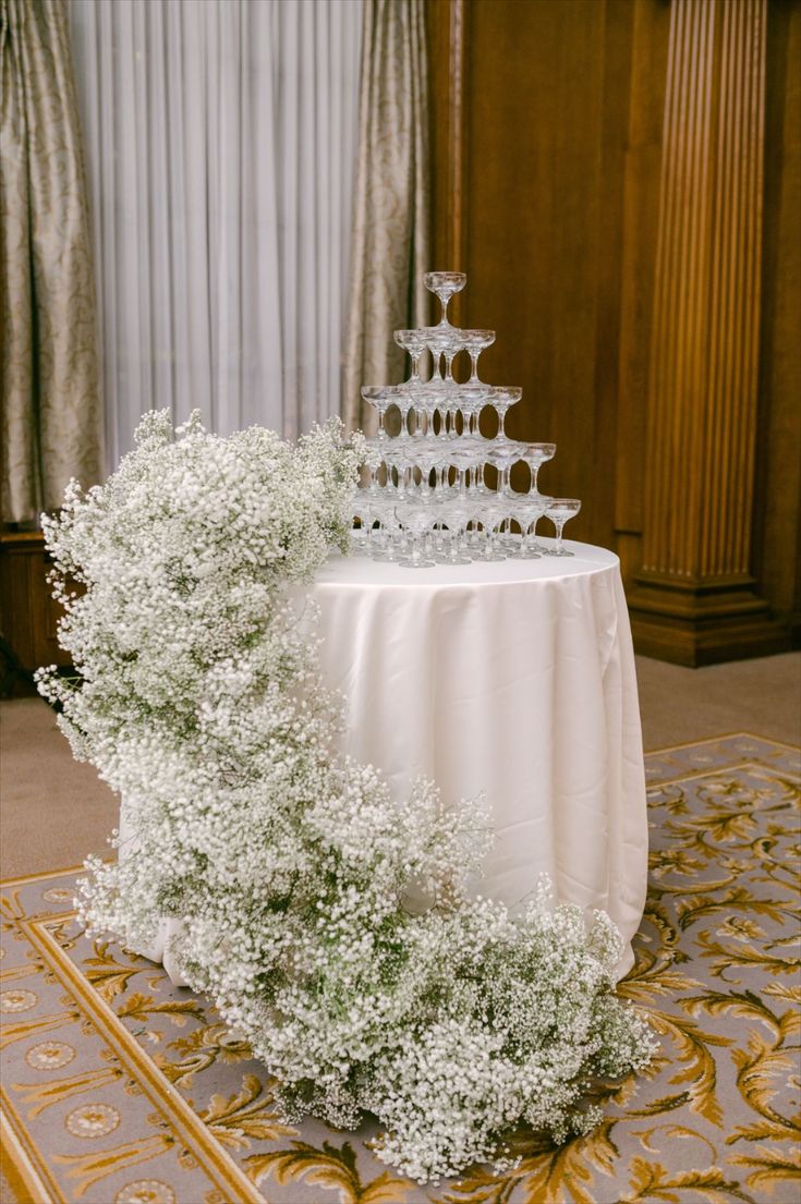 a table topped with a cake and flowers on top of a white tablecloth covered floor