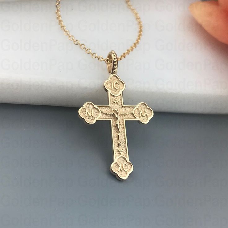 a gold cross necklace on a white cloth