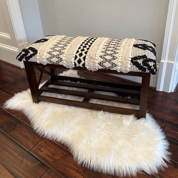 a bench that is sitting on the floor in front of a wall with a rug