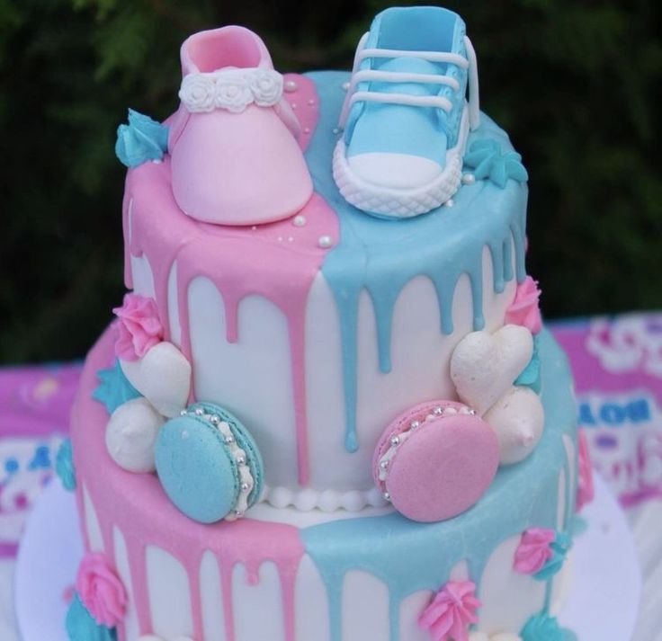 a cake decorated with baby shoes and pink, blue, and white icing on a table