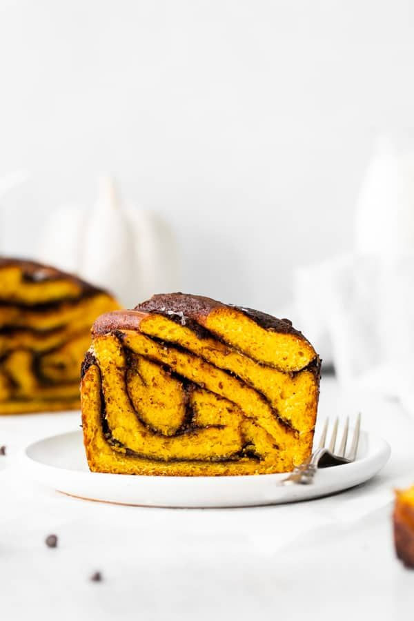 a piece of cinnamon roll on a white plate with a fork next to the cake