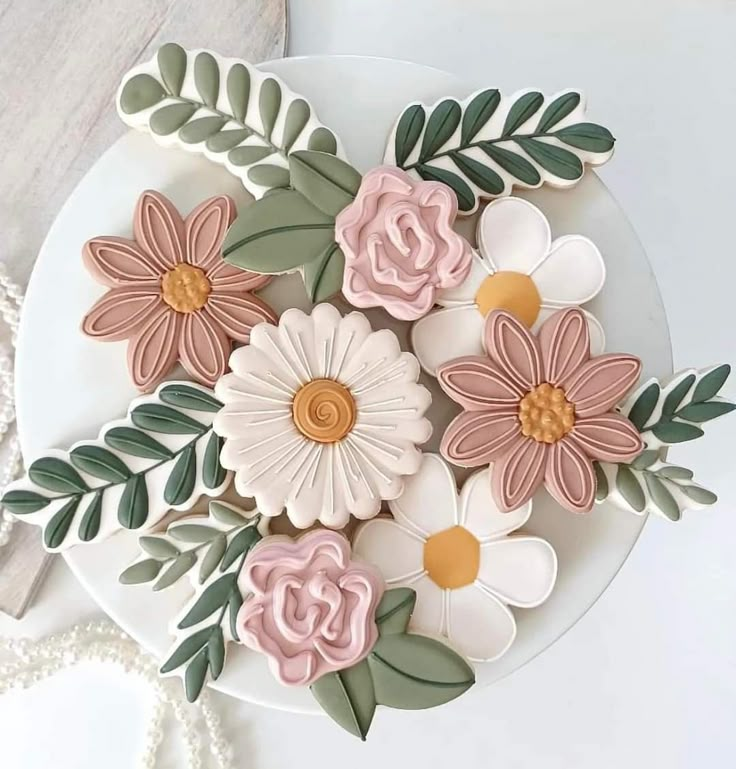 decorated cookies with flowers and leaves on a plate