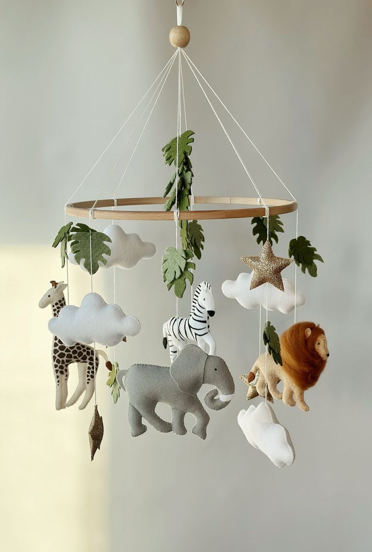 an animal mobile is hanging from the ceiling with leaves and other animals on it's sides