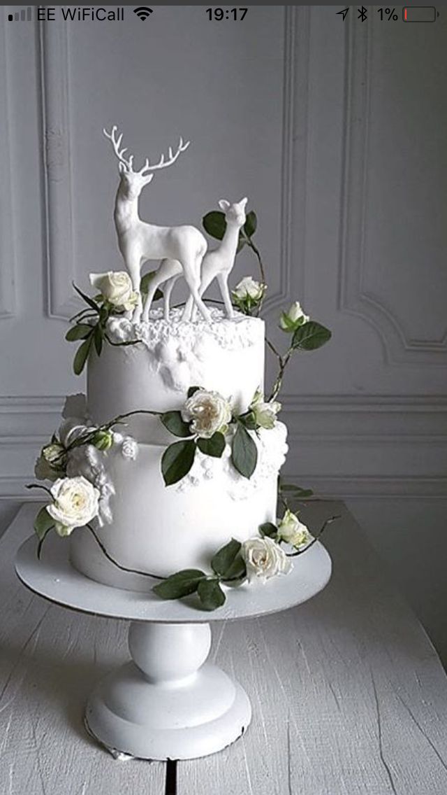 a white wedding cake decorated with flowers and deer figurines