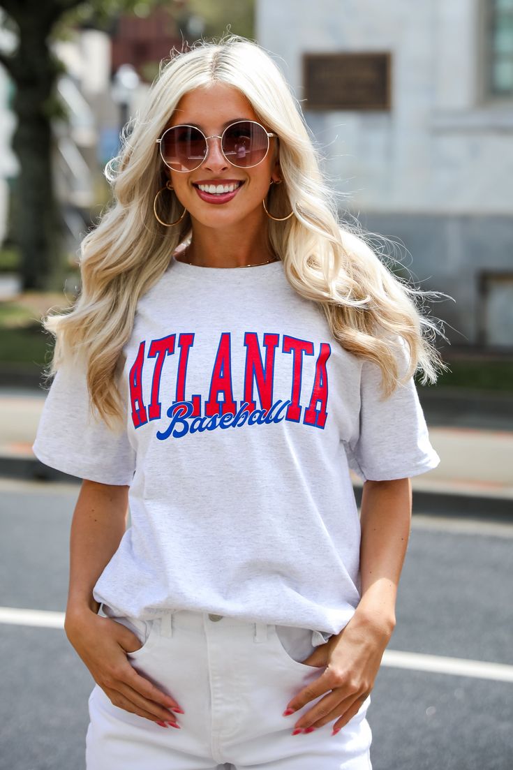 Calling all Braves fans, the Heather Grey Atlanta Baseball Tee was made just for you! This comfy tee is designed with a soft and stretchy knit. It features a crew neckline, short sleeves, a relaxed fit, and the words "Atlanta Baseball" on the front. Style the Heather Grey Atlanta Baseball Tee with your favorite distressed denim and a baseball hat for the perfect game day look! Champion Brand Soft + Stretchy Knit Fabrication "Atlanta Baseball" Graphic Crew Neckline Short Sleeves Relaxed Fit 100% Sporty T-shirt For Spring Fan Merchandise, Casual Cotton T-shirt For Game Day, Varsity Style Relaxed Fit Crew Neck T-shirt, College Style Short Sleeve T-shirt For Game Day, Casual Stretch T-shirt With Letter Print, Stretch Crew Neck T-shirt With Text Print, Game Day Graphic Tee With Crew Neck, Graphic Tee Crew Neck T-shirt For Game Day, Graphic Tee Crew Neck For Game Day