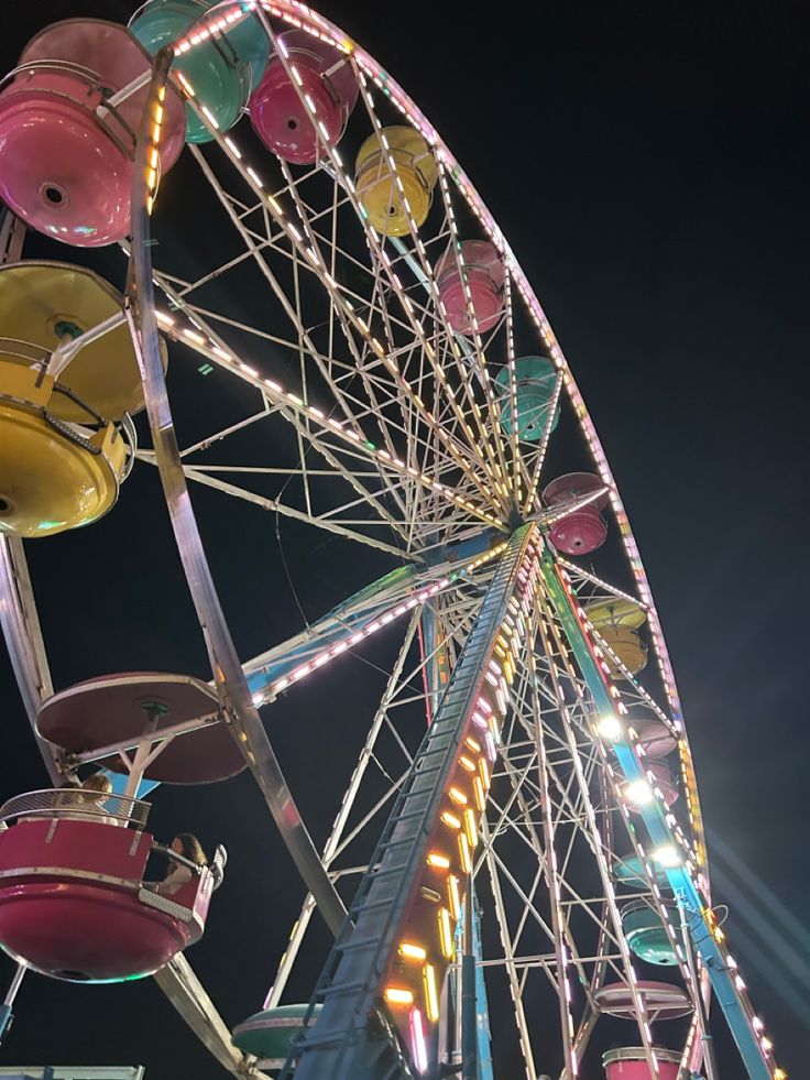 the ferris wheel is brightly lit up at night