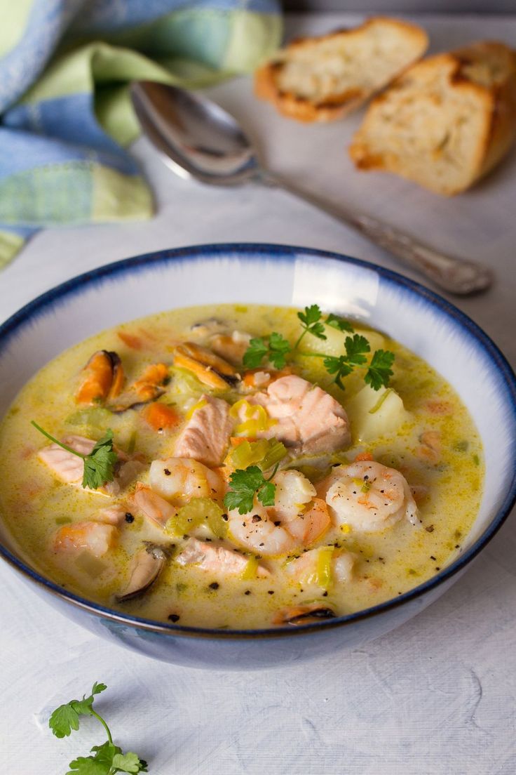 a bowl of soup with shrimp and bread