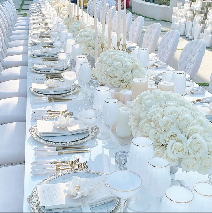 a long table set with white flowers and place settings for formal dinner or wedding guests