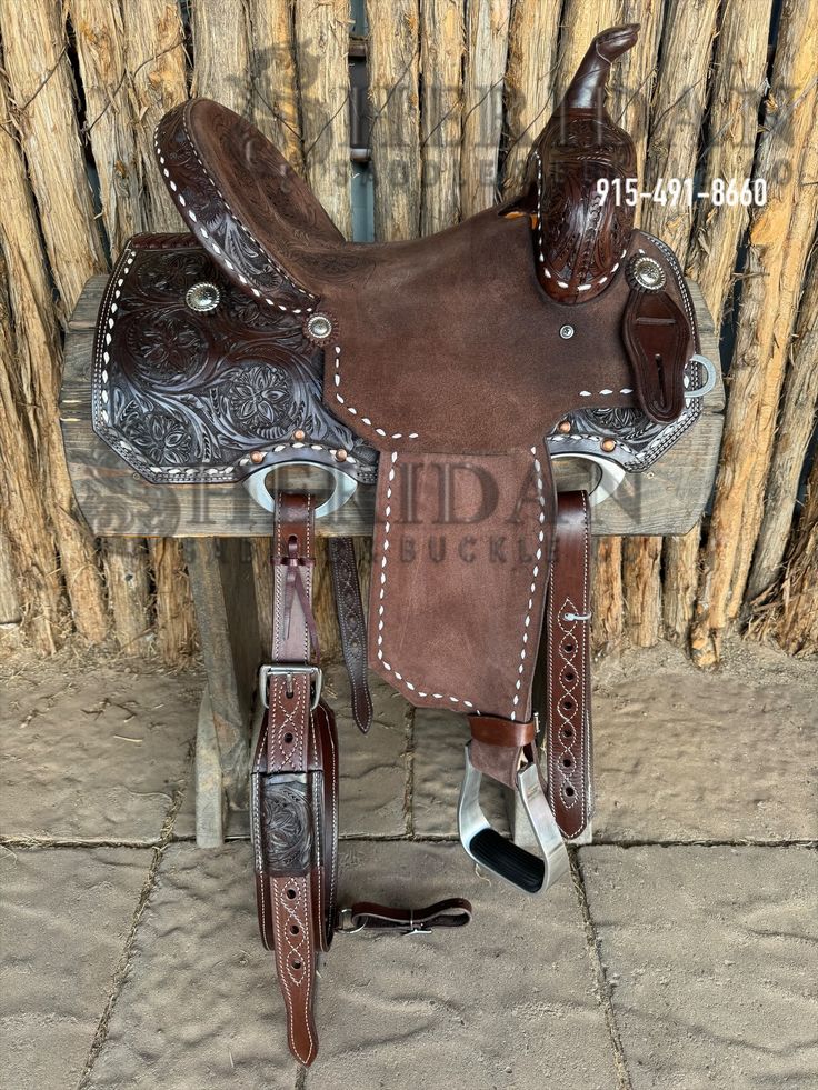 a brown saddle sitting on top of a wooden bench