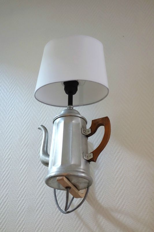 a lamp that is on the wall with a tea pot attached to it and a wooden handle