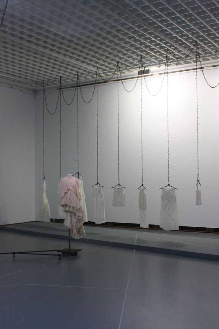 an empty room with several pieces of clothing hanging from the ceiling