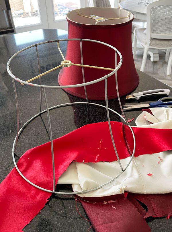 a red lamp shade sitting on top of a black table next to a white chair