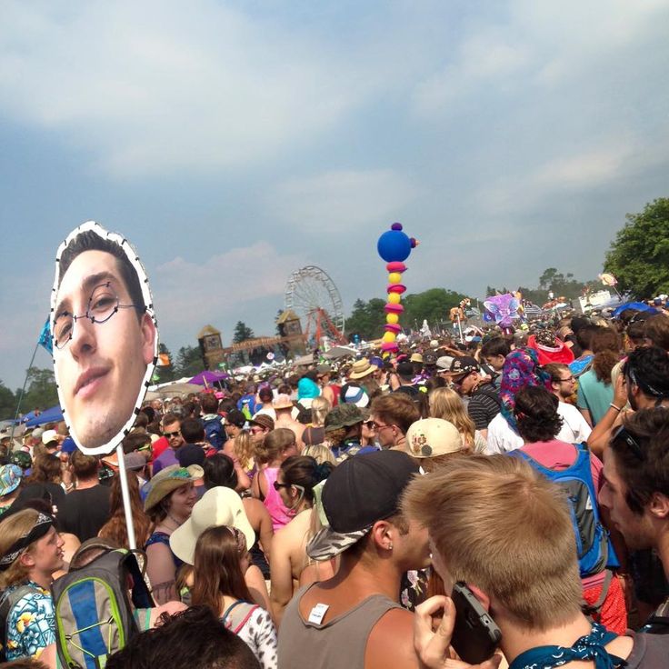 a large group of people standing around each other at a music festival with a giant photo of frisbee in the air