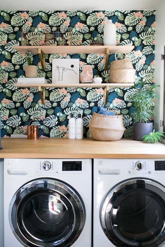 a washer and dryer sitting in front of a wall with plants on it