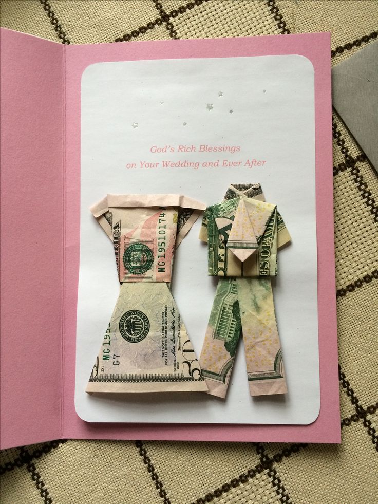 an origami man and woman made out of money on top of a card