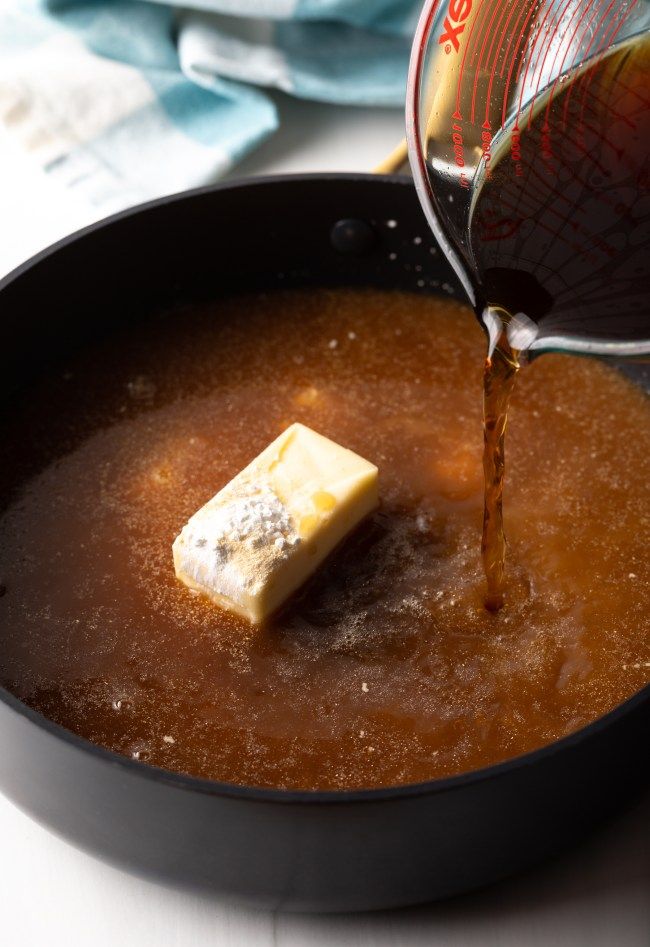 a pan filled with sauce and butter being poured into it