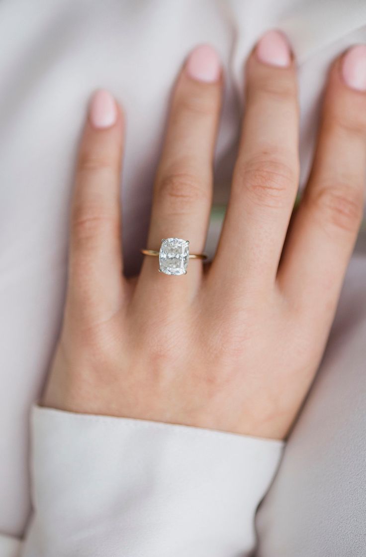 a woman's hand with a diamond ring on top of her left hand,