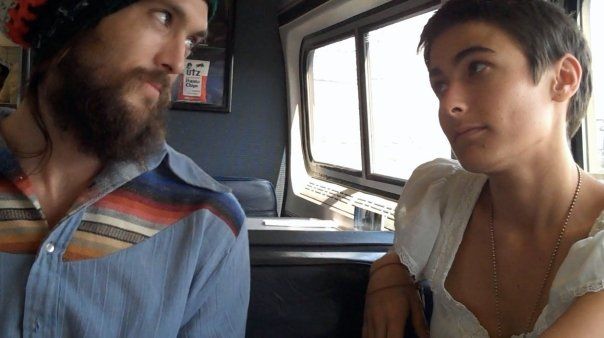 a man and woman sitting next to each other on a bus looking out the window