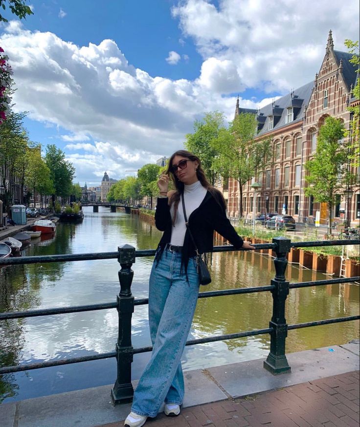 a woman standing on a bridge next to a body of water