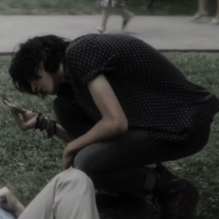 a woman kneeling down next to a man on the ground with scissors in his hands