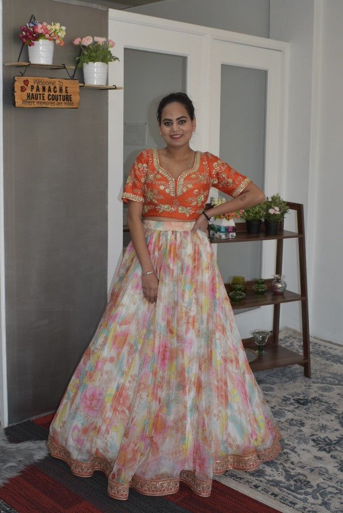 Adorning Partywear Designer Floral Lehenga Choli Orange splendor! This outstanding and eye-catching Wrinkle Chiffon Silk Floral lehenga choli makes you stand out among others when you adorn it. The skirt of this lehenga is made up of wrinkle chiffon silk and beautified with floral digital print. The hem of the skirt is adorned with marodi work that adds a sign of magnificence statement to your look. It is paired with a raw silk blouse, which is embellished with hand embroidery work. The lehenga Navratri Reception Anarkali Set, Orange Georgette Sets For Festivals, Multicolor Chanderi Anarkali Set For Reception, Designer Cutdana Choli In Maxi Length, Chanderi Gown With Gota Work For Reception, Gota Work Chanderi Gown For Reception, Fitted Multicolor Floor-length Anarkali Set, Orange Georgette Sets For Reception, Traditional Maxi Length Lehenga With Gota Work