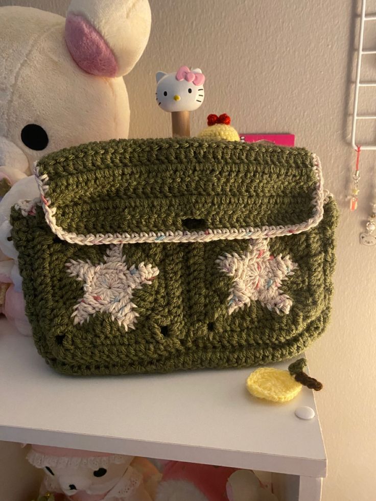 a green crocheted purse sitting on top of a table next to a stuffed animal