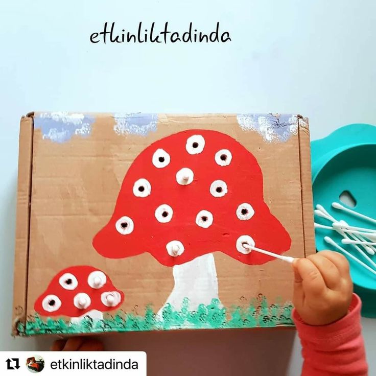 a child is painting a mushroom on a cardboard box