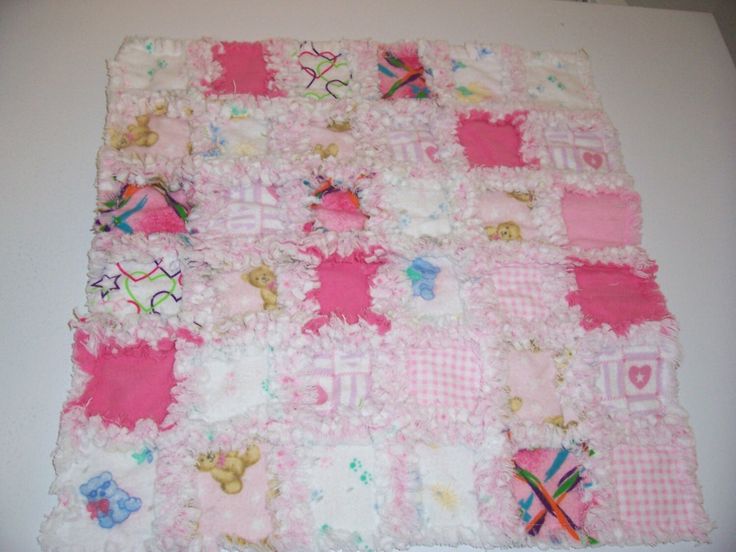 a pink and white patchwork blanket with teddy bears on the top, sitting on a table