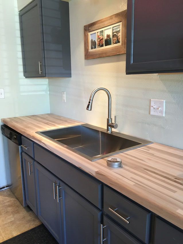 a kitchen sink with wooden counter tops and black cabinets