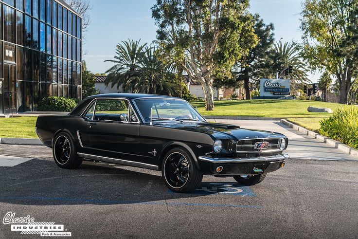 an old black mustang parked in front of a building