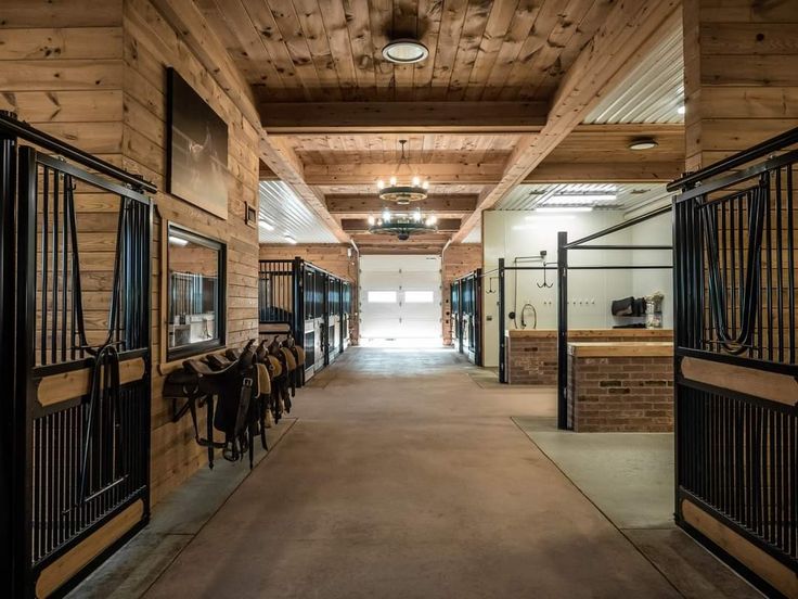 the inside of a building with several stalls and horses in pens on either side of the doors