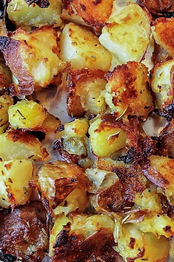 cooked potatoes with herbs and seasoning on a baking sheet, ready to be eaten