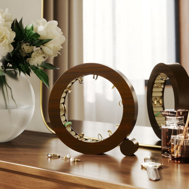 a vase with white flowers and two rings on a table next to other items in front of a mirror