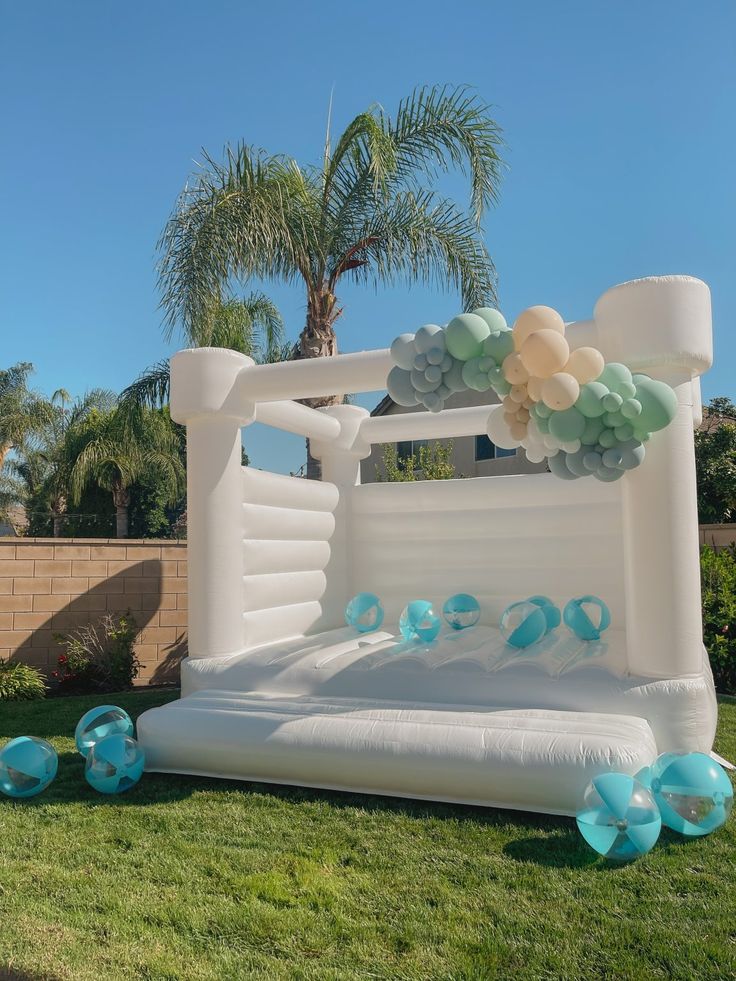 an inflatable bed is set up on the lawn with balloons and streamers